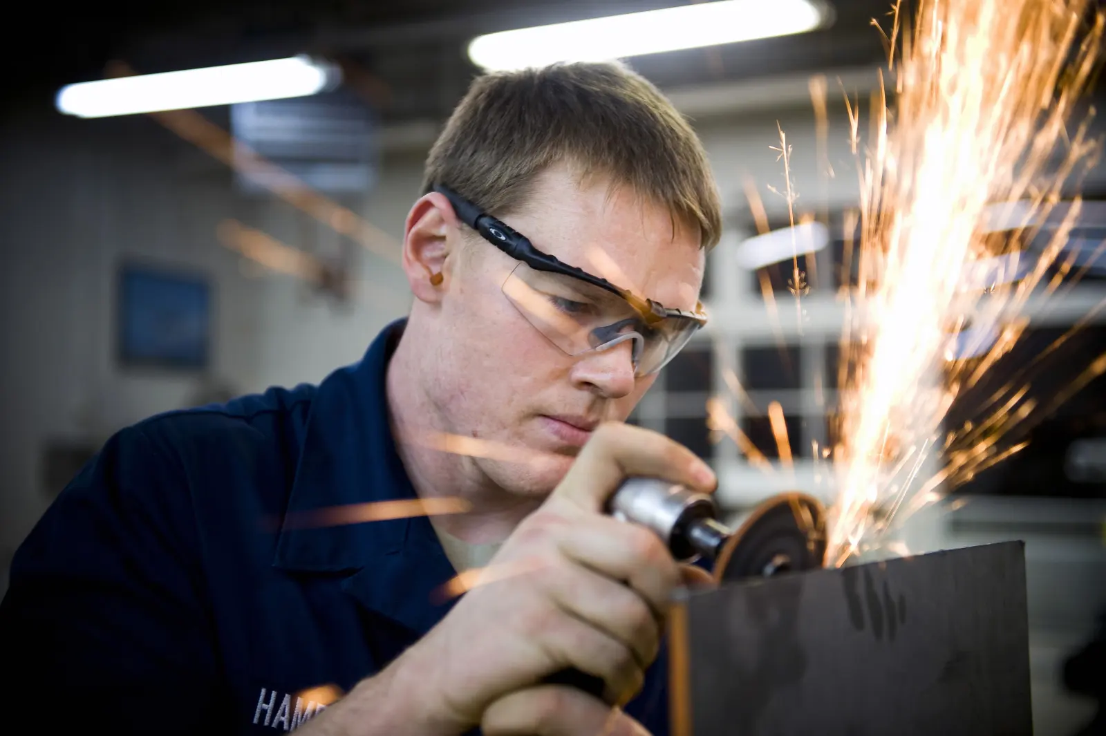 Worker in safety glasses grinding metal